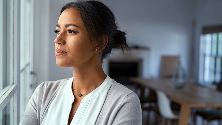 Woman gazes out window deep in thought 