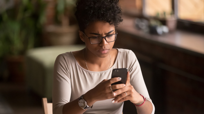 annoyed woman looking at smartphone