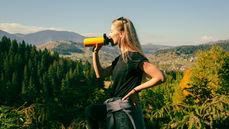 Woman drinking water on mountain