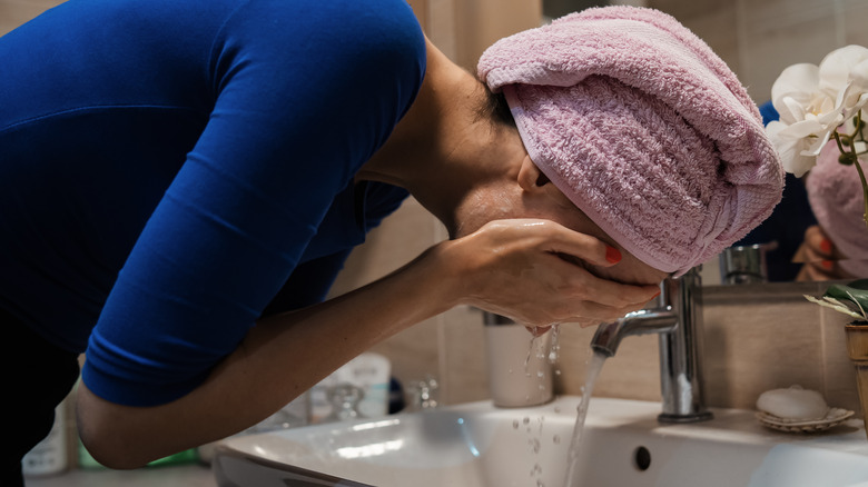 Woman cleaning face in sink