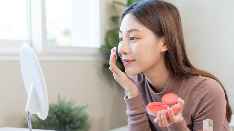 Woman applying blush on cheek