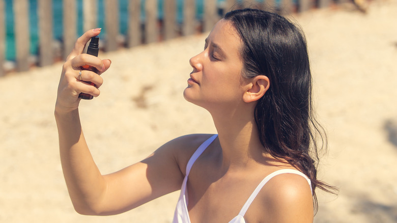 Woman spraying sunscreen