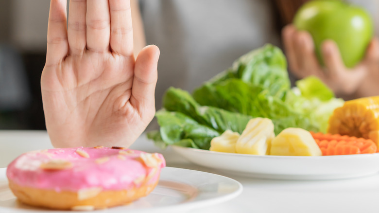 hand refusing donut for vegetables