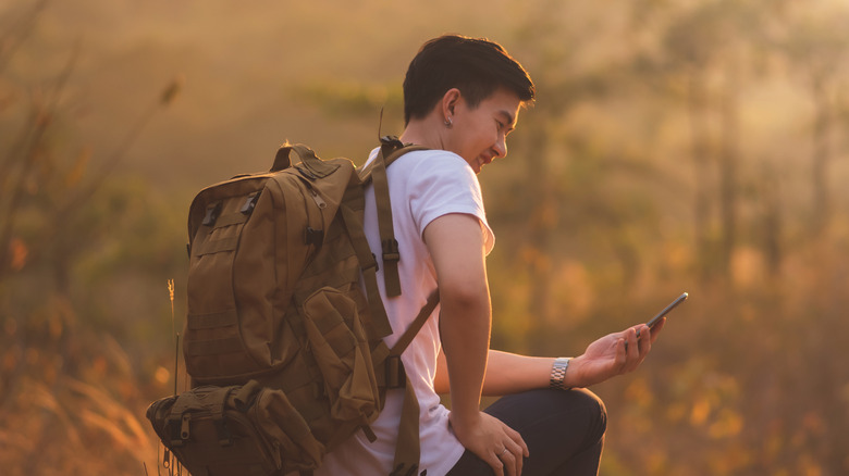 Asian man checking phone during hike