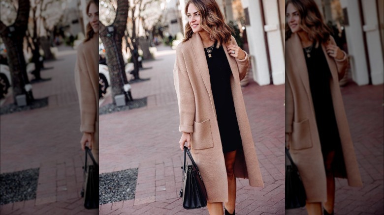 Woman walks down brick sidewalk in black dress and coatigan