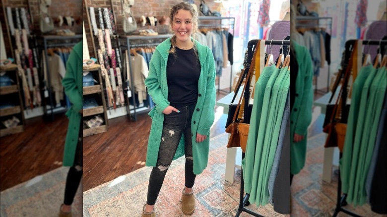 Woman poses in dark wash jeans, black tee, and green coatigan 