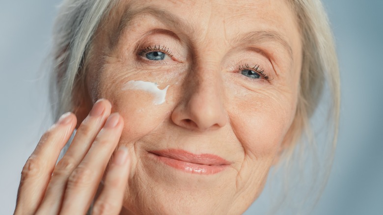 woman applying cream on face