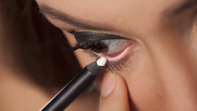 woman applying white eyeliner