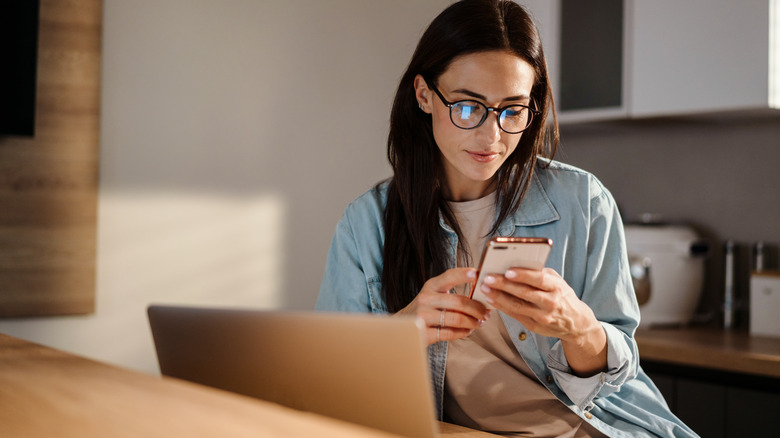 Woman uses phone and laptop