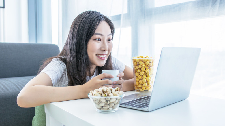 Woman happily watches laptop screen