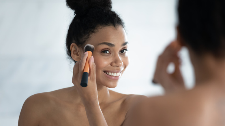 Smiling woman applying makeup