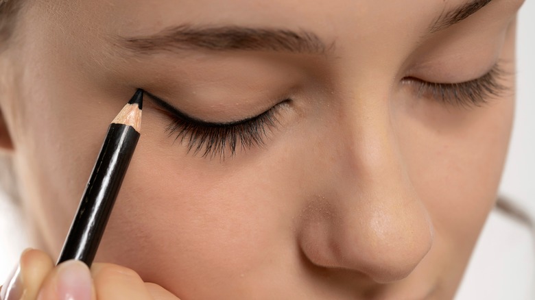 Woman applying liner to eyelids