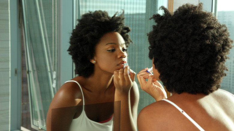 woman putting on lipstick