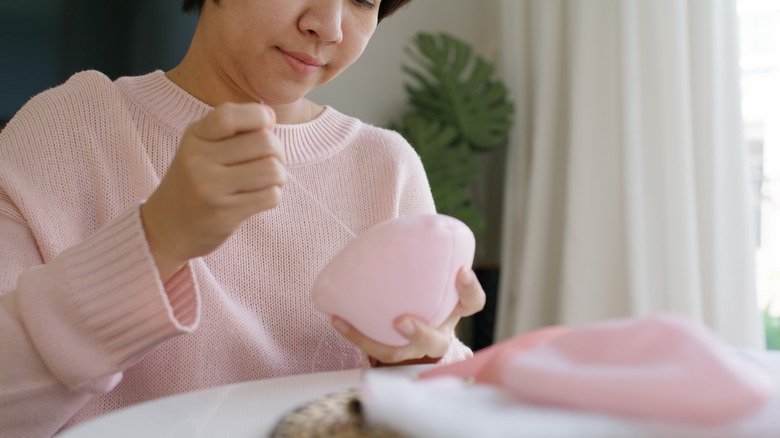 woman holding a pink bra cup