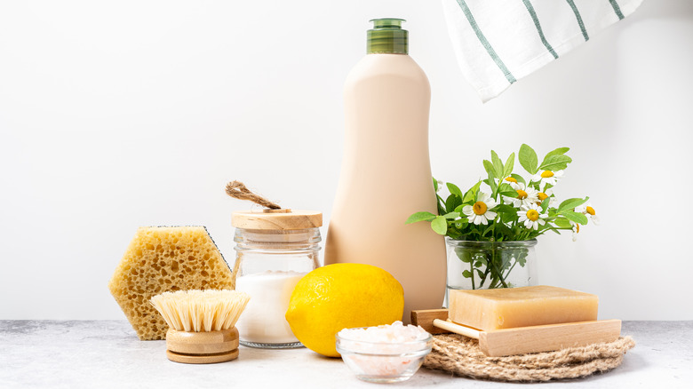 set of environmentally friendly wooden cleaning products displayed with lemon and flowers