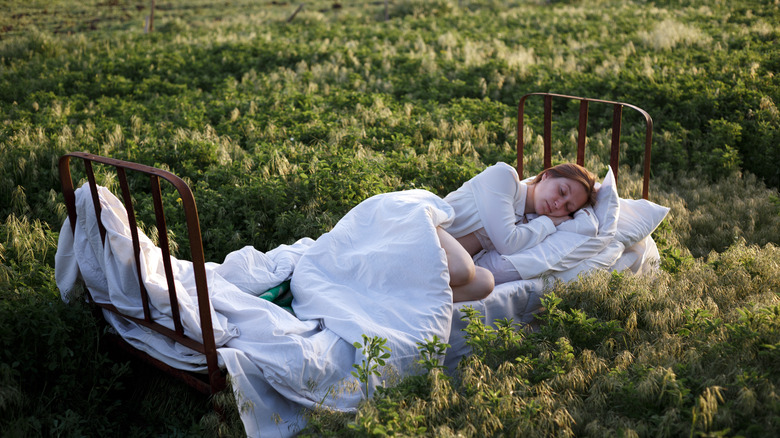 A woman sleeping in a bed of grass