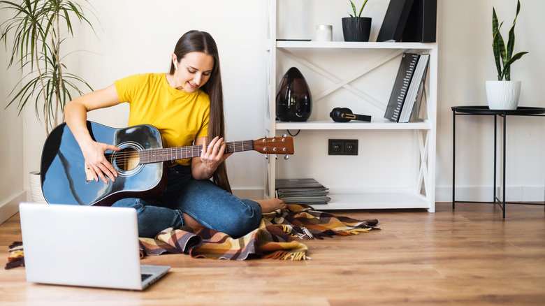 Woman practicing guitar on floor