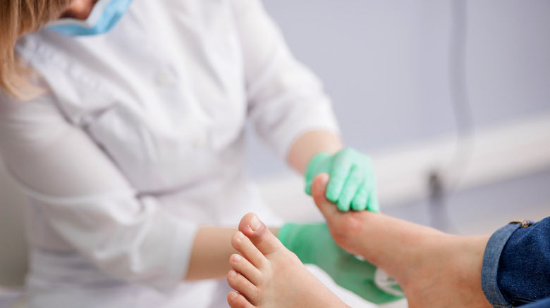 podiatrist examines patient's foot