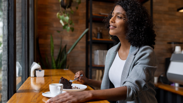 Woman eating cake alone at cafe