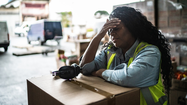 Woman leans over box at work
