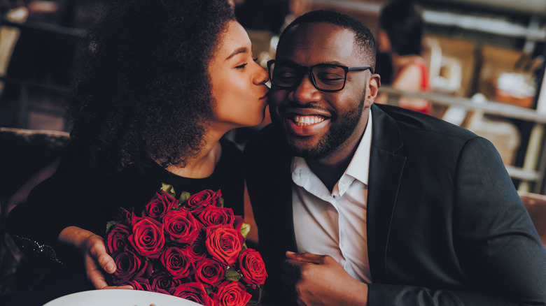 African American couple on a date at a restaurant, woman kissing man on cheek