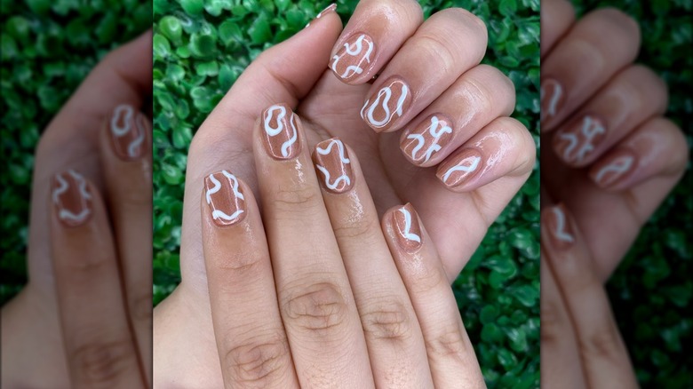 Rose gold fingernails with white squiggles 