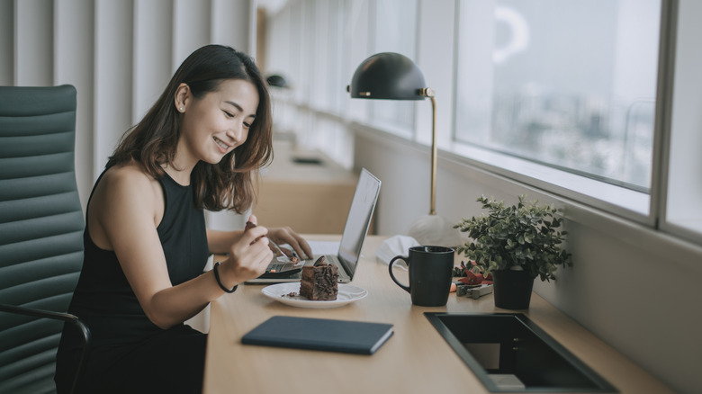 Woman eating cake at desk