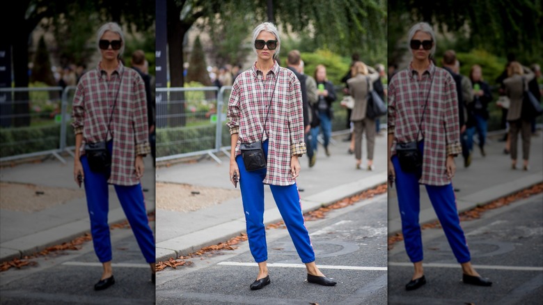 Woman posing on street wearing blue joggers and plaid shirt