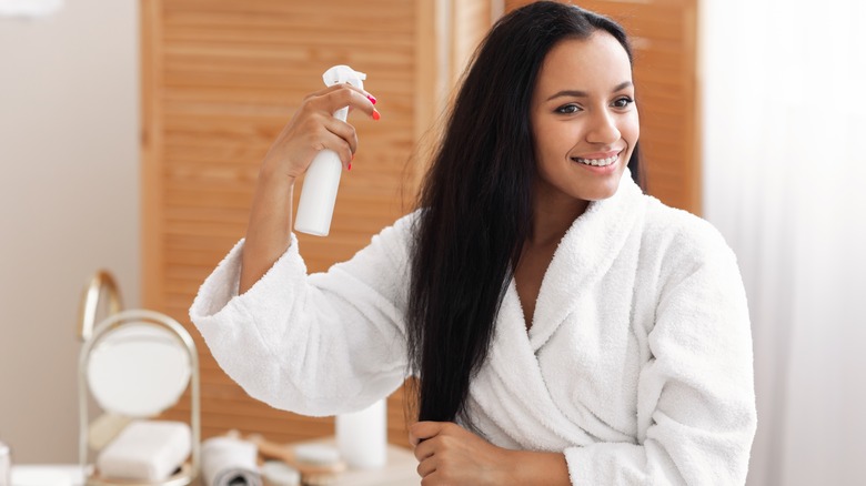 Woman spraying detangler on hair