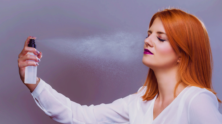 woman spraying setting spray on face