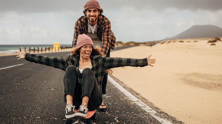 man pushing woman on skateboard