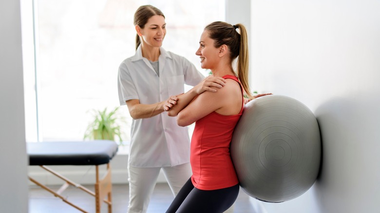 Woman helping client do squats