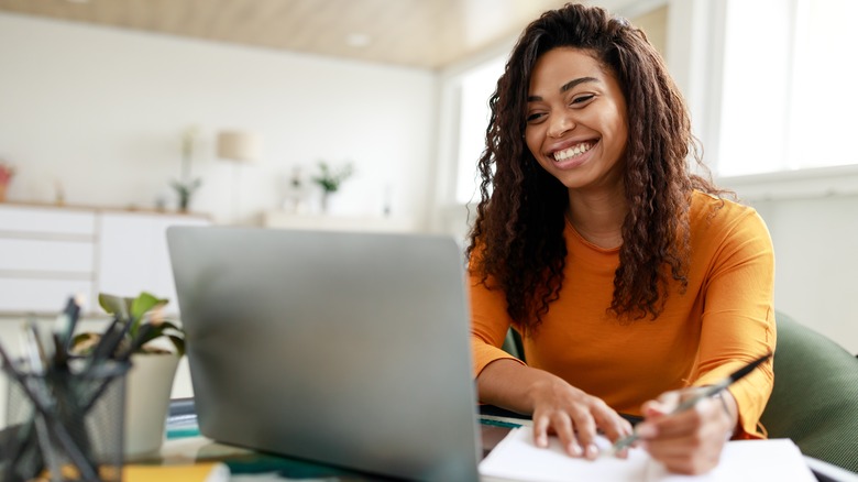 Woman in front of laptop making notes