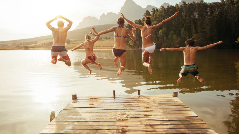 Group of friends jumping into lake