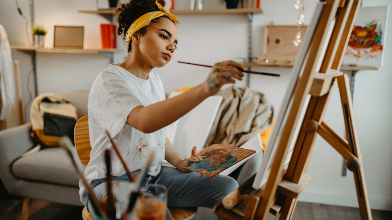 Woman painting at easel 