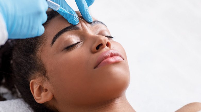 young woman getting injection between eyebrows