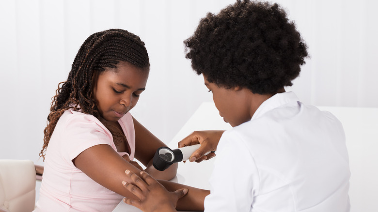 Doctor examining girl's skin