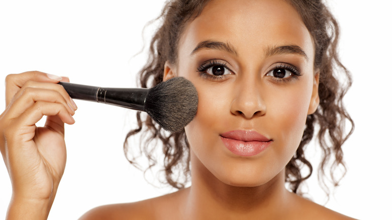 Woman applying blush with a large brush