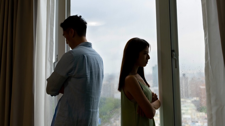 Two people facing away by window