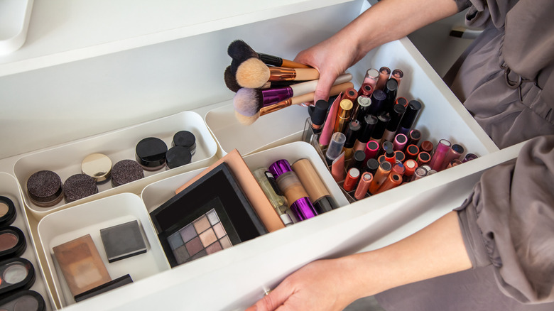 woman taking makeup brushes out of drawer