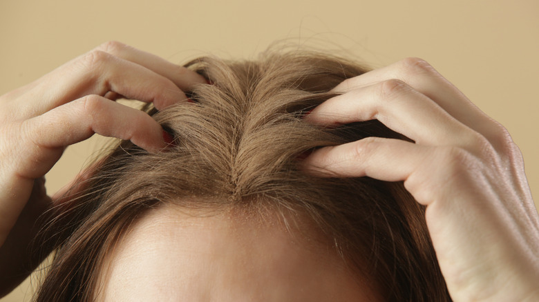 Woman applying dry shampoo to her scalp