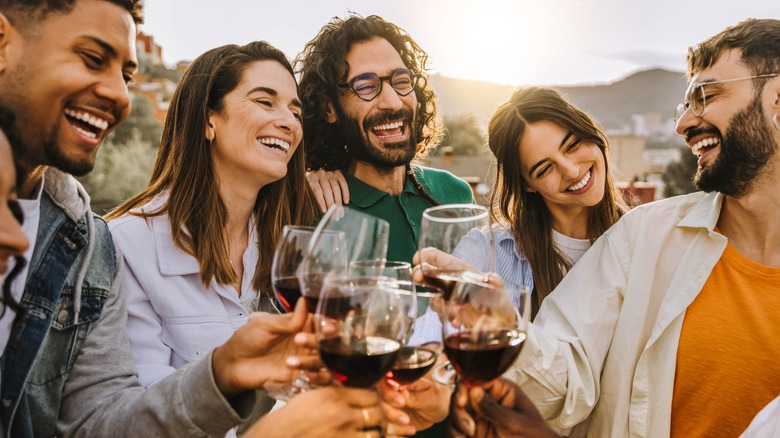 Smiling friends clinking wine glasses