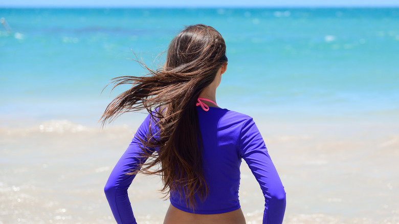 Woman on the beach staring at water