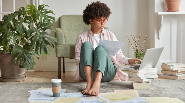 Woman surrounded by many stacks of papers, books, and ideas