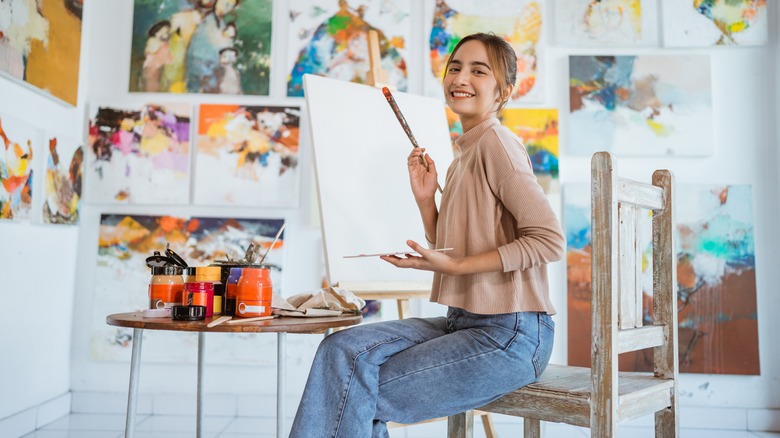 Young woman in arty studio prepares to paint masterpiece