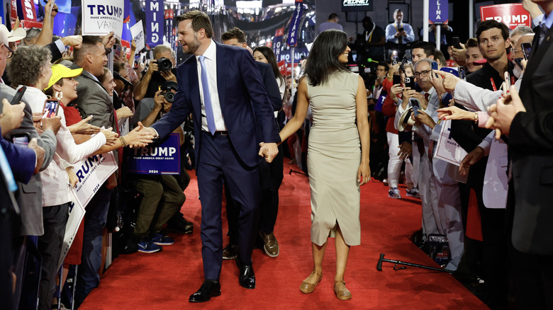 Usha Vance wearing a beige sheath dress as she arrives at the 2024 RNC with her husband.