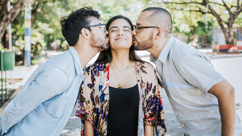 Two men kissing one woman