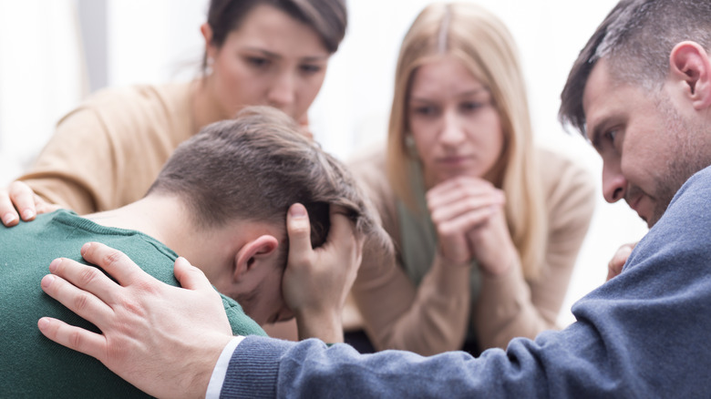 man being comforted by friends