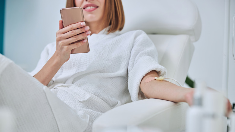 woman on phone while receiving IV 