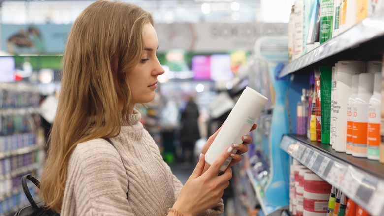 woman looking at shampoo bottle at store